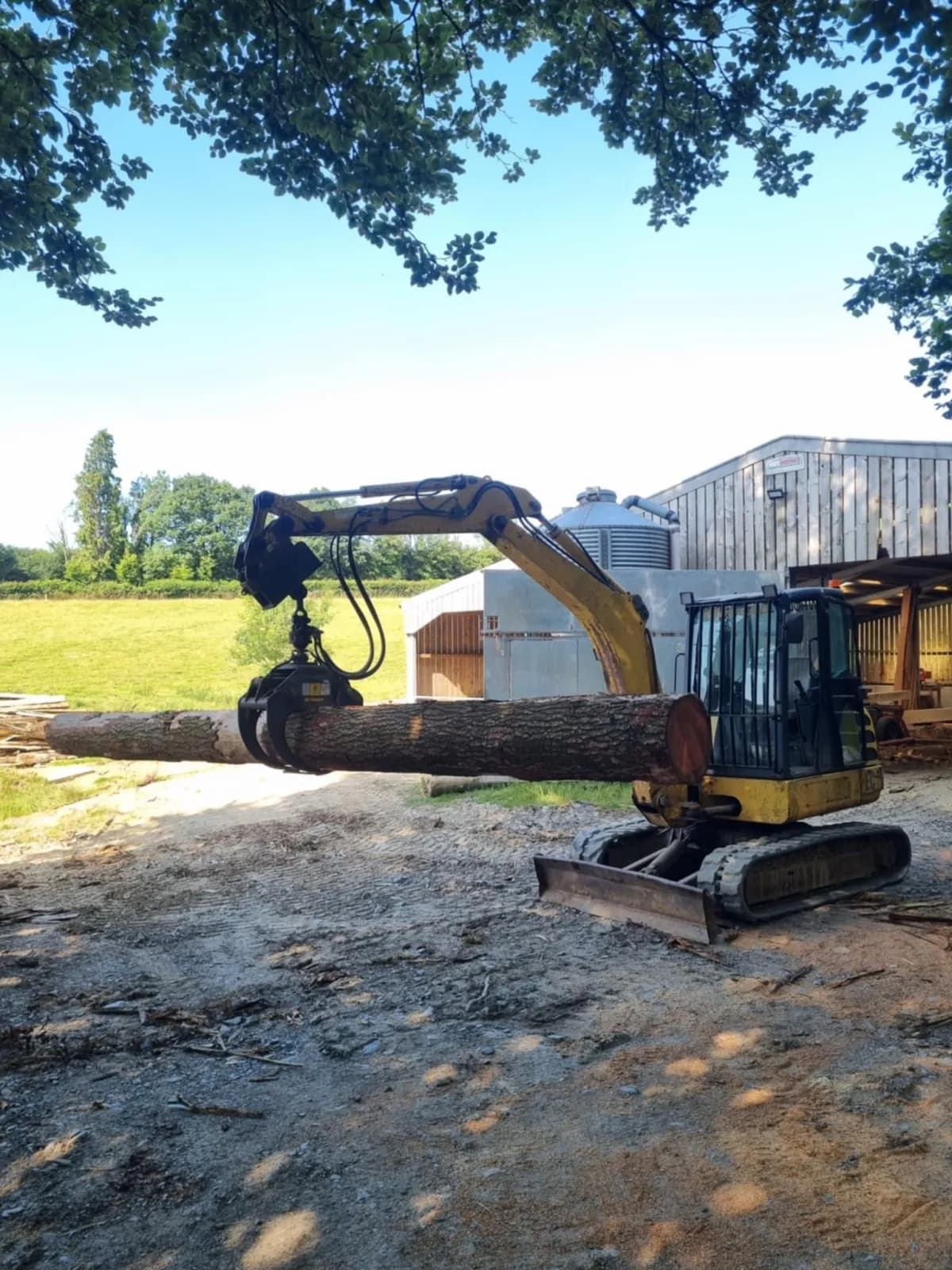 Excavator grapple lifting a log onto the mill
